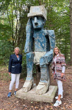 Zwei Frauen stehen neben Skulptur im Wald