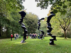 Personengruppe hinter Skulpturen in Park